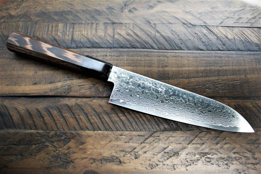 An image of a santoku knife on a dark wooden surface. What is a santoku knife used for?