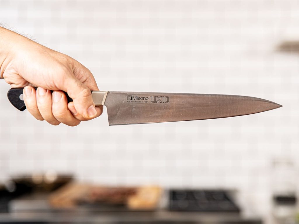 An image of someone holding a chef knife using the handle grip. What is the safest way to hold a chef knife? This person's never heard of safety before.