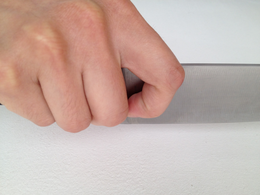 An image of a closeup on a hand holding a chef knife properly. 