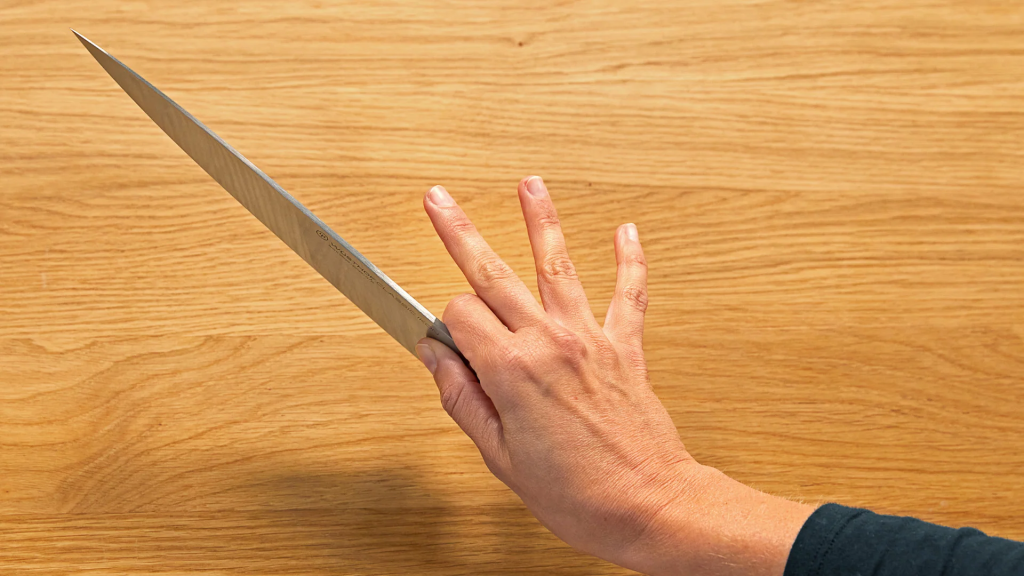 An image displaying someone holding their chef knife in the pinch grip. The best grip for your chef knife.